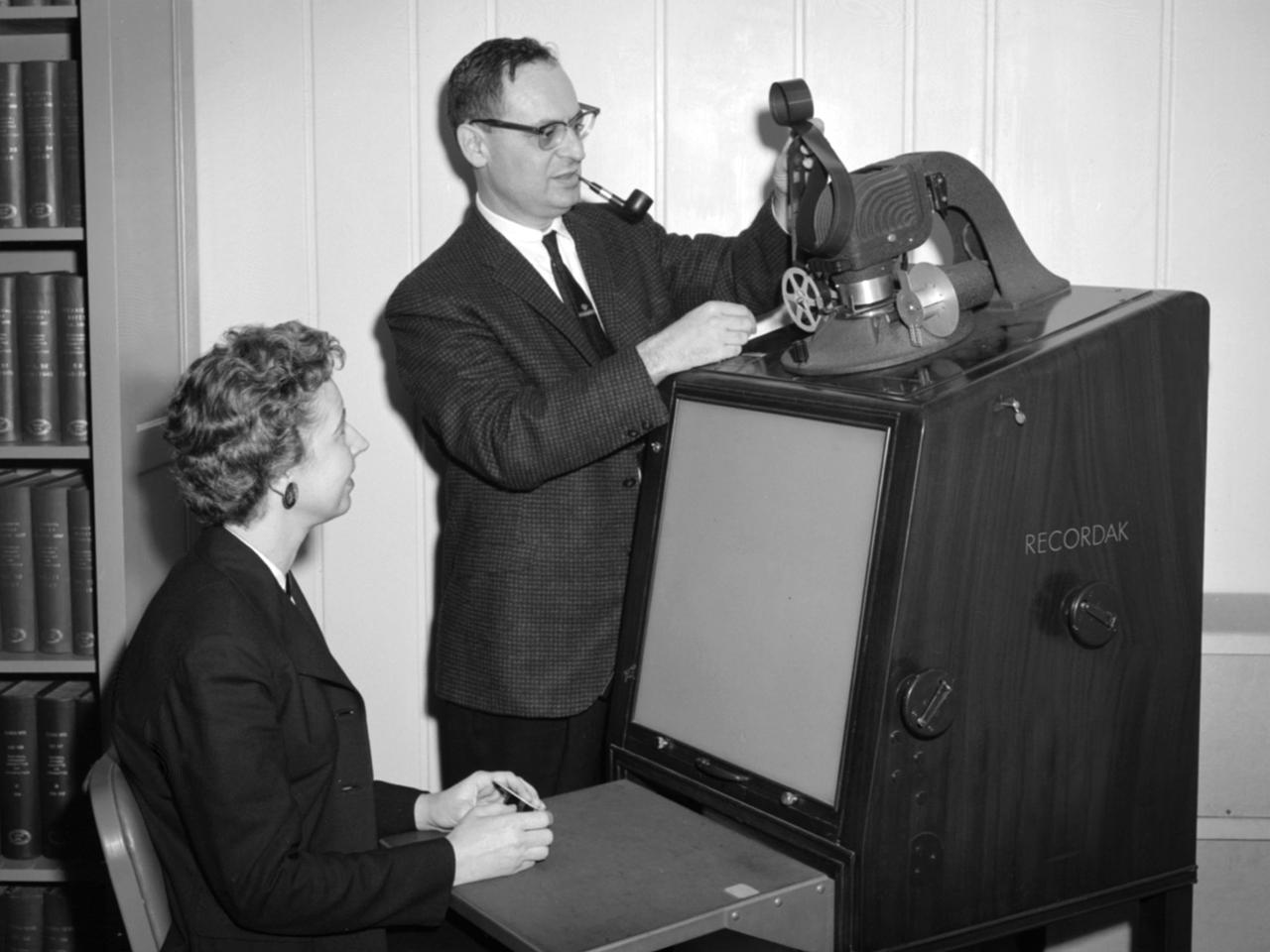 NASA Lewis Research Center library staff operating a microfilm reader for archival research.